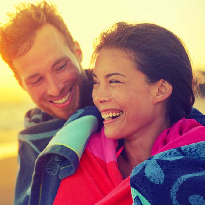 Romantic couple with towel on beach sunset during vacation